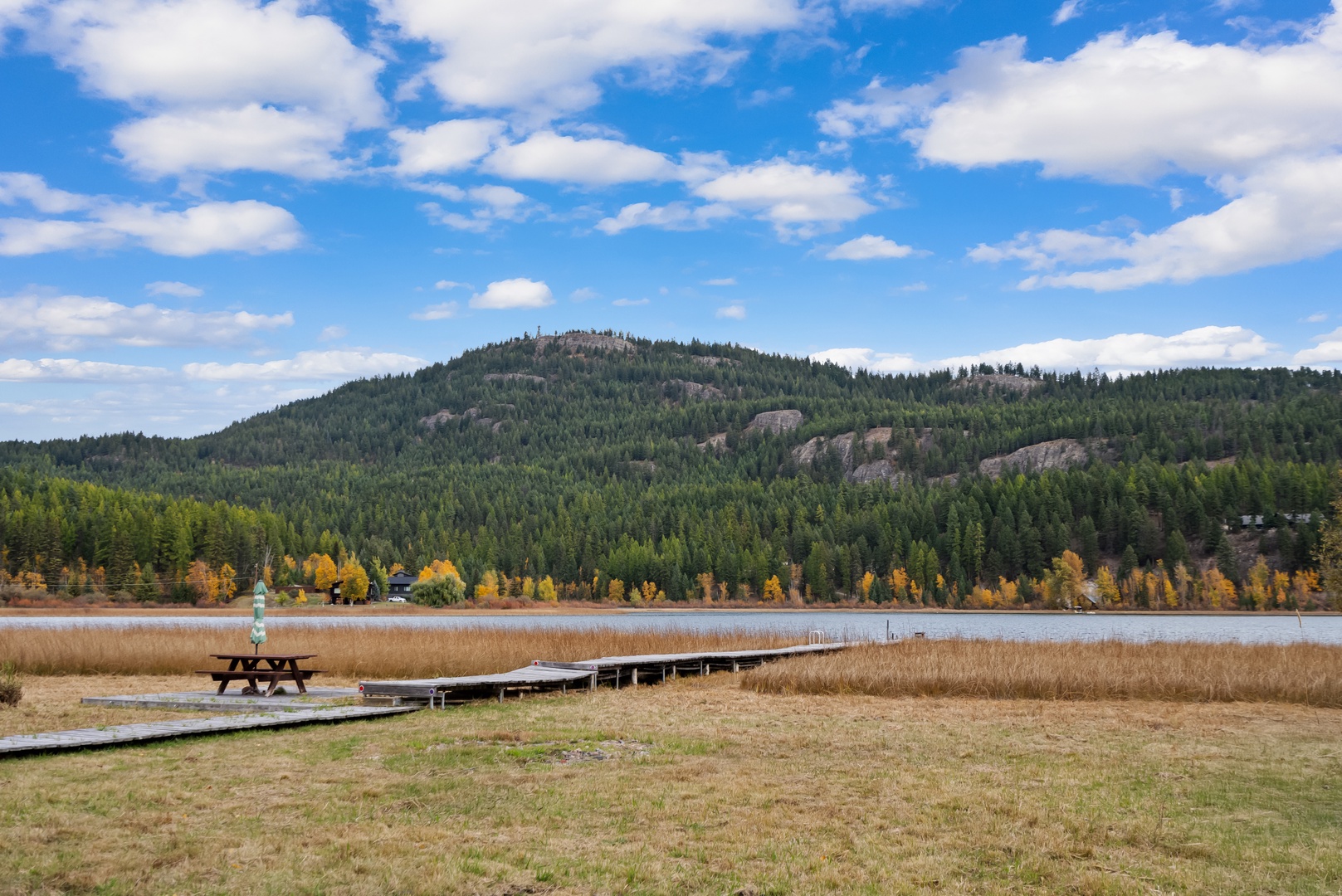 Scenic lakeside location surrounded by forested mountains and autumn colors, with dock and picnic area nearby.