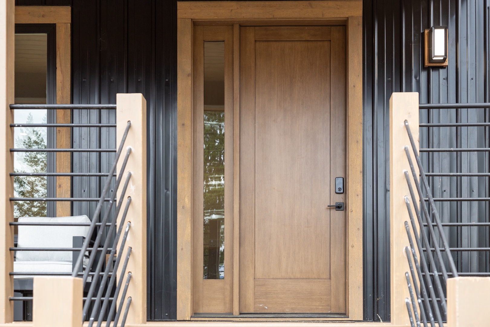 Modern entry door with natural wood framing and sleek metal accents defines the property's welcoming entrance.