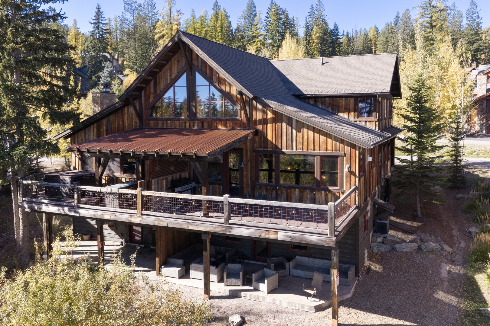 A stunning mountain chalet nestled in the forest with expansive decks, rustic wood siding, and soaring windows that flood the interior with natural light—your perfect alpine escape awaits.