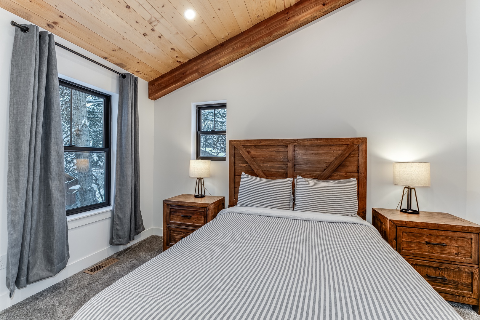 Drift off peacefully in your cozy bedroom with rustic wood ceiling beams and forest views outside your windows.