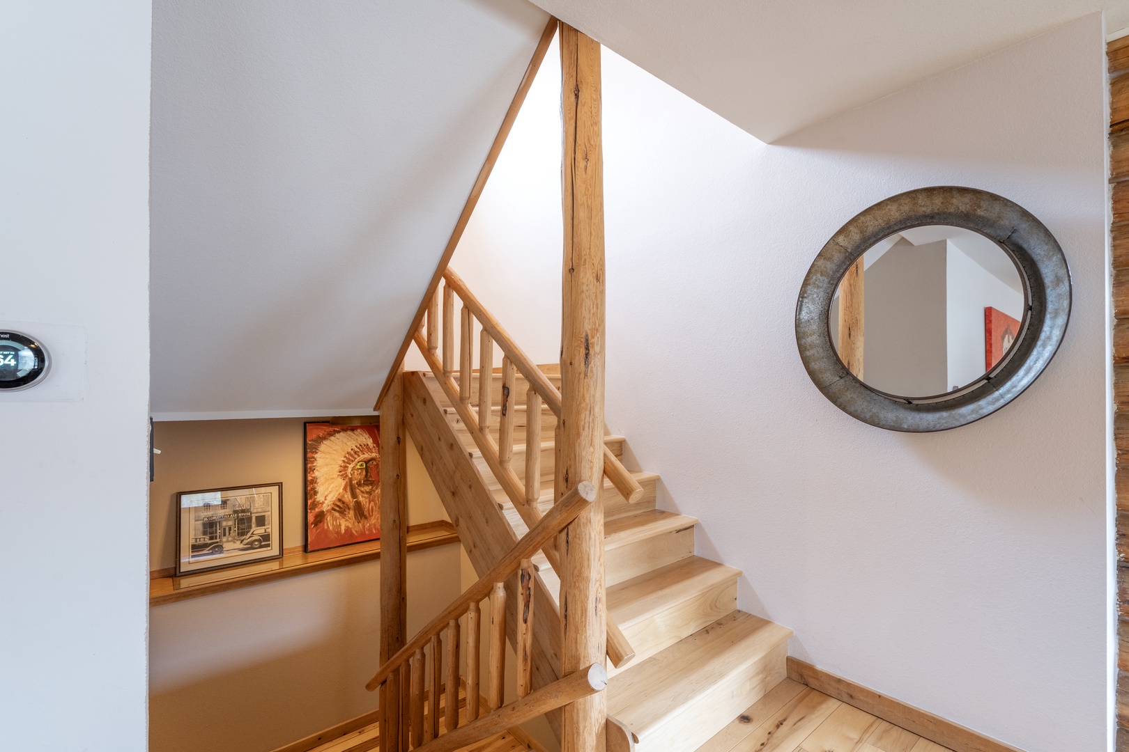 Warm wooden stairs lead you to your private retreat, with charming details like the rustic mirror creating a welcoming atmosphere.