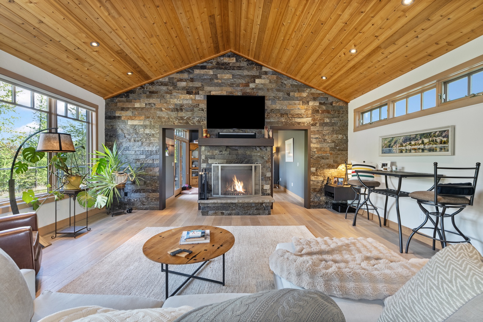 Gather around the warmth of your stone fireplace and soak in natural light streaming through vaulted ceilings—this inviting space blends rustic charm with modern comfort for your perfect mountain escape.