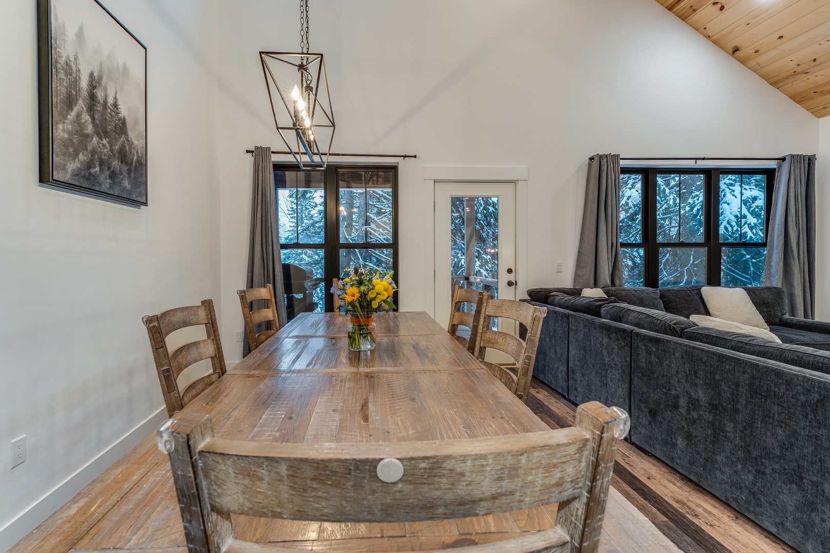 Gather around your rustic dining table where warm wood meets modern comfort, perfect for sharing meals beneath the striking pendant light.