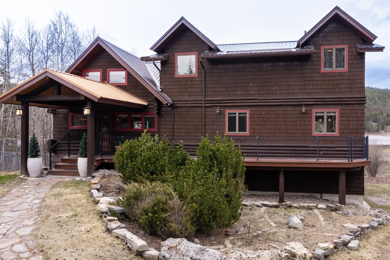 A striking mountain retreat with modern shingle architecture, featuring natural stone landscaping and forest surroundings for your peaceful getaway.