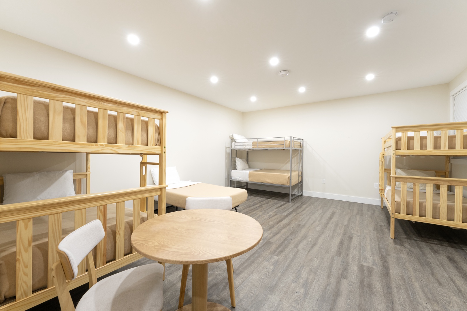 Bright, spacious sleeping quarters with natural wood bunk beds and a central gathering table—perfect for groups or families traveling together.