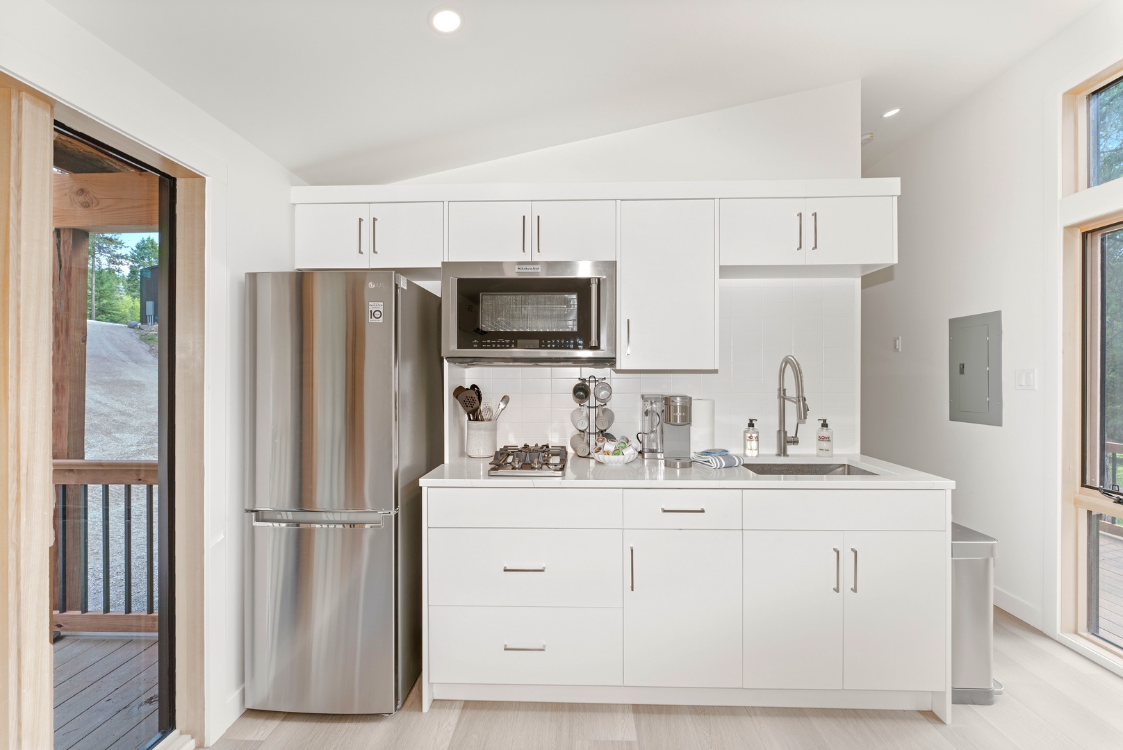 Your bright, modern kitchen features sleek white cabinets and stainless appliances, perfect for preparing meals during your stay.