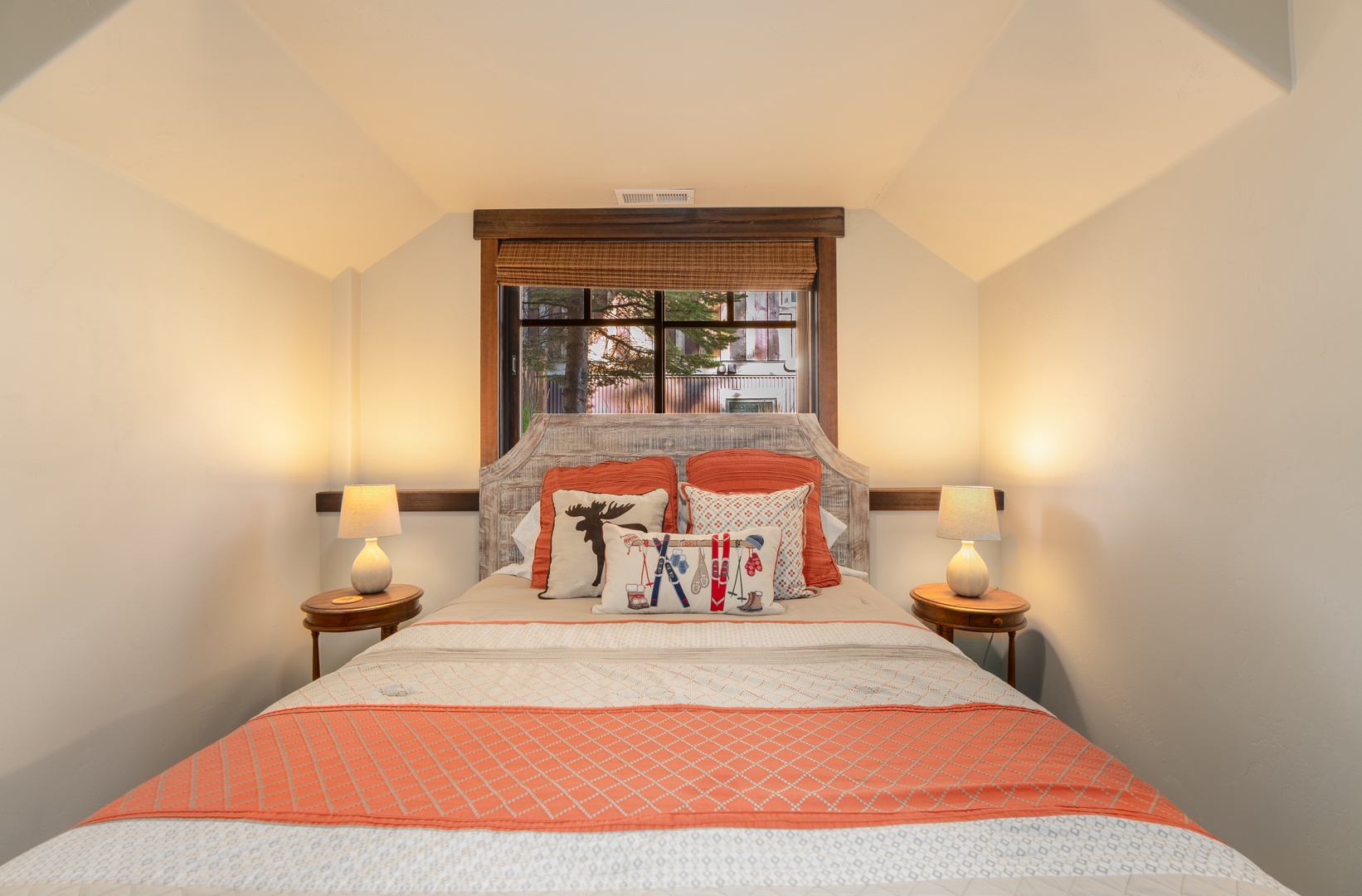 Curl up in your cozy upstairs bedroom, where vaulted ceilings and warm lighting create the perfect retreat after a day on the slopes. The rustic wood accents and playful ski-themed pillows bring a touch of mountain charm to your restful sanctuary.