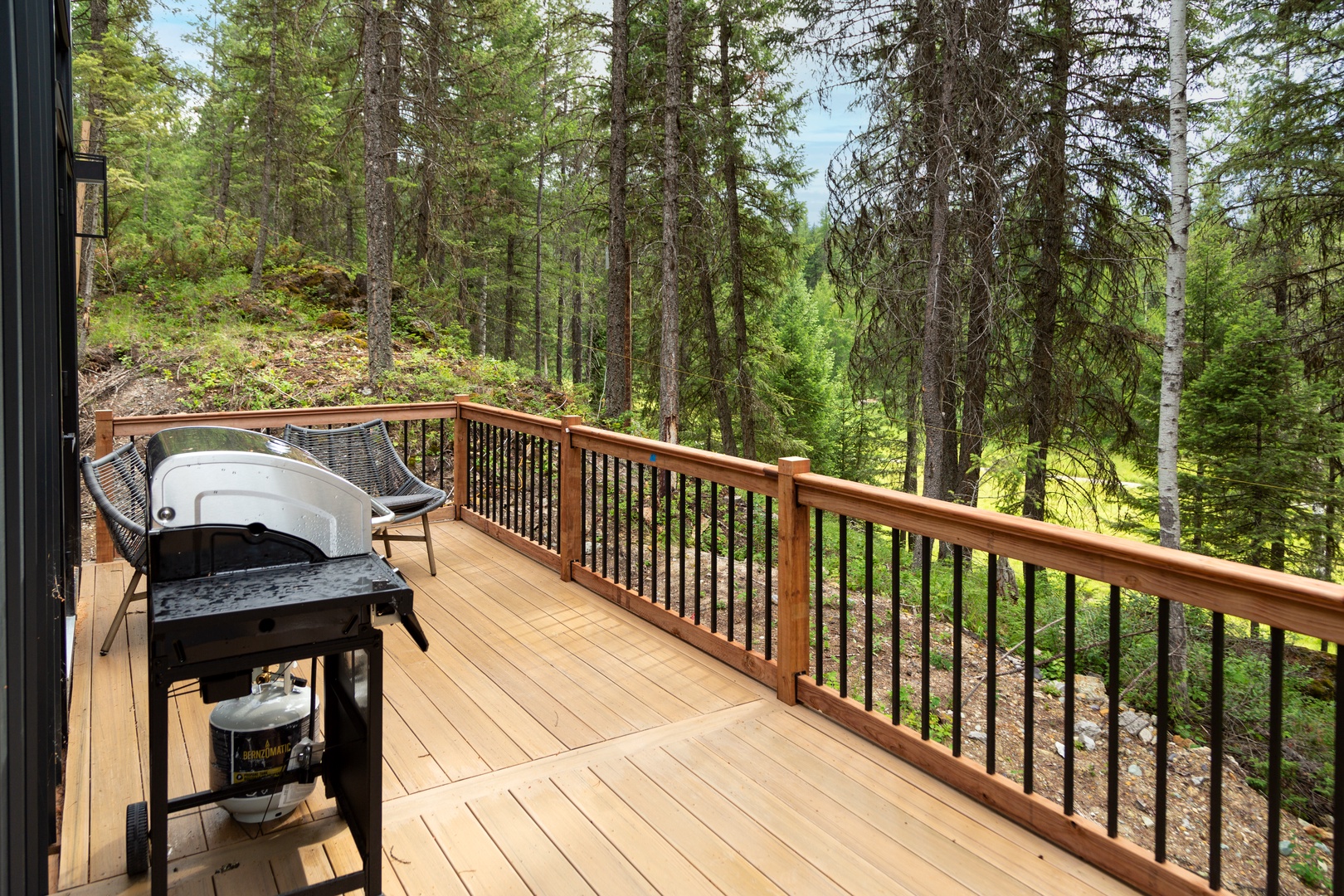 Step out onto your private wooden deck, where a BBQ grill awaits and towering evergreens surround you—perfect for peaceful mornings or starlit evenings in nature.
