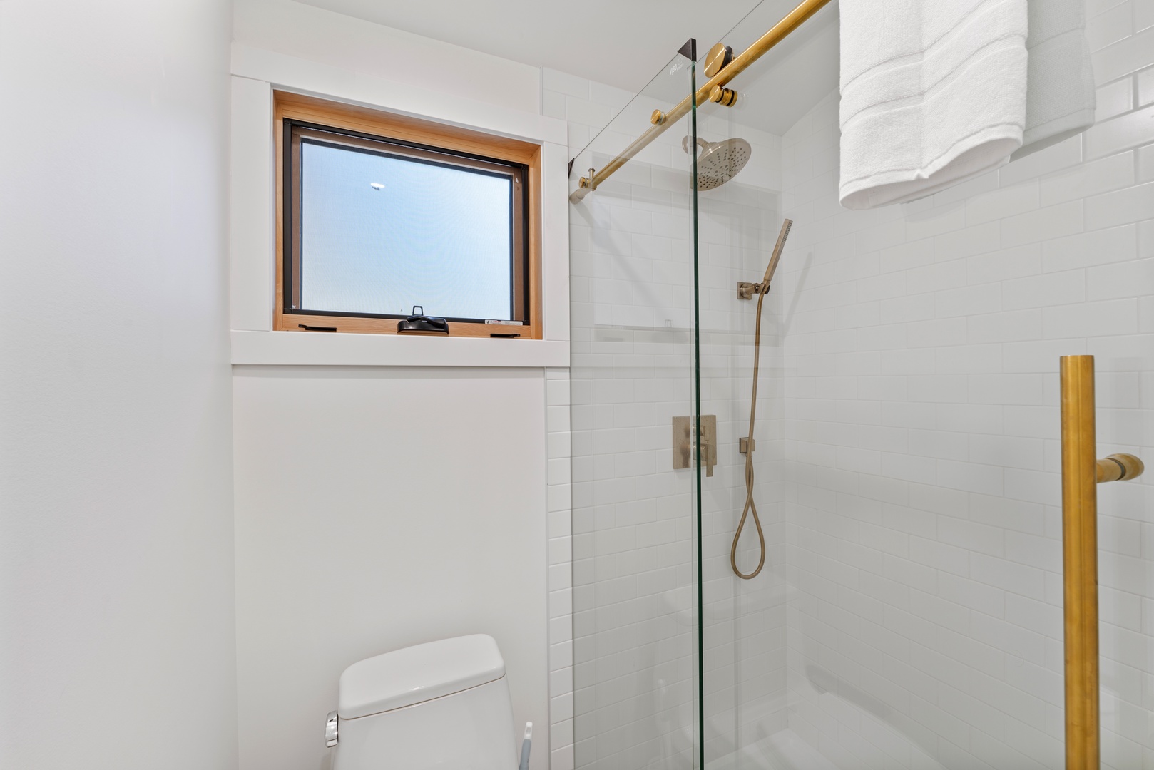 Step into your pristine bathroom featuring elegant white subway tiles, warm gold fixtures, and a spacious walk-in shower perfect for refreshing after your adventures.