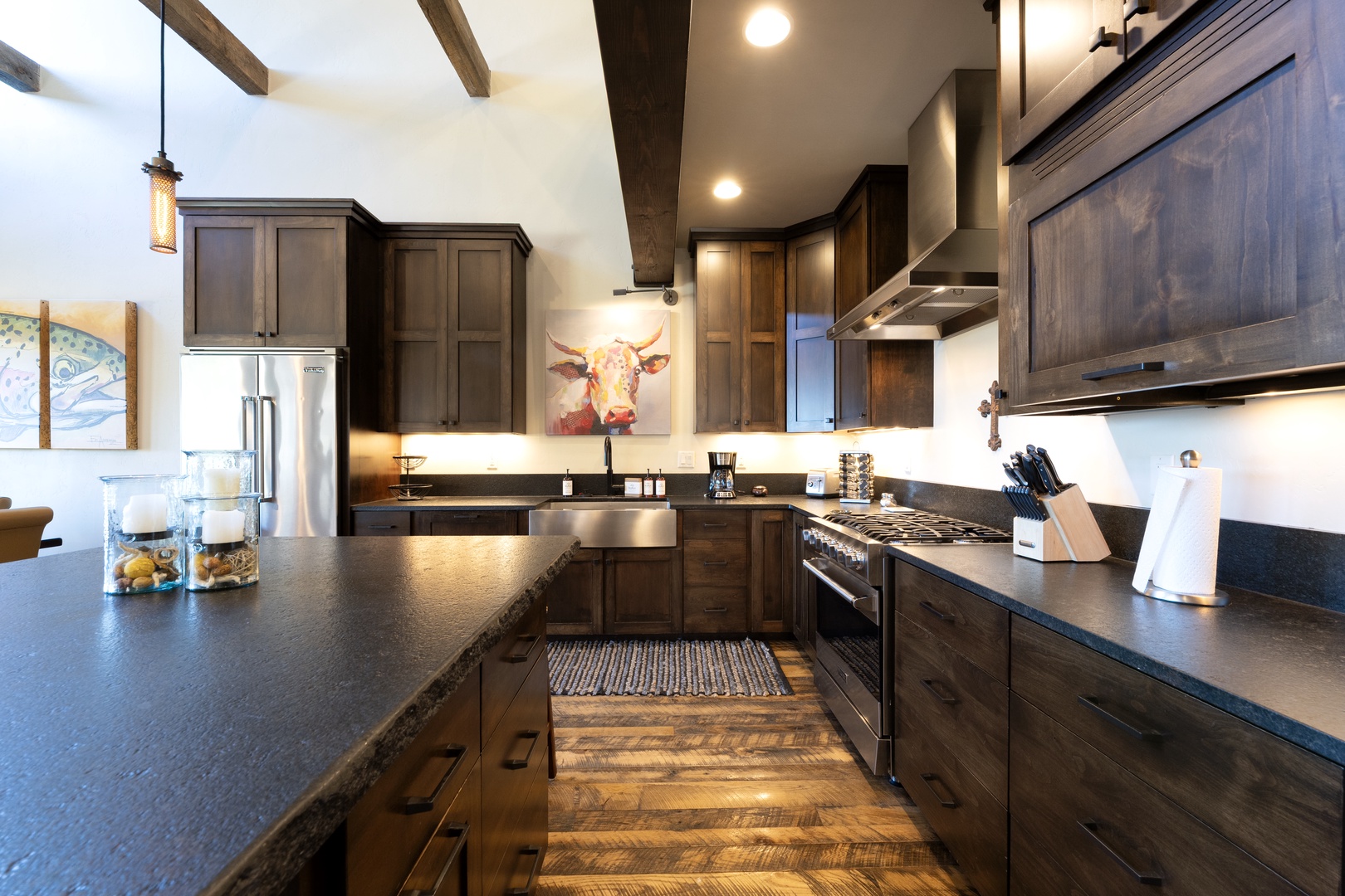 A spacious, chef-ready kitchen awaits your culinary adventures, featuring professional-grade appliances, ample counter space, and warm wood cabinetry beneath striking exposed beams.