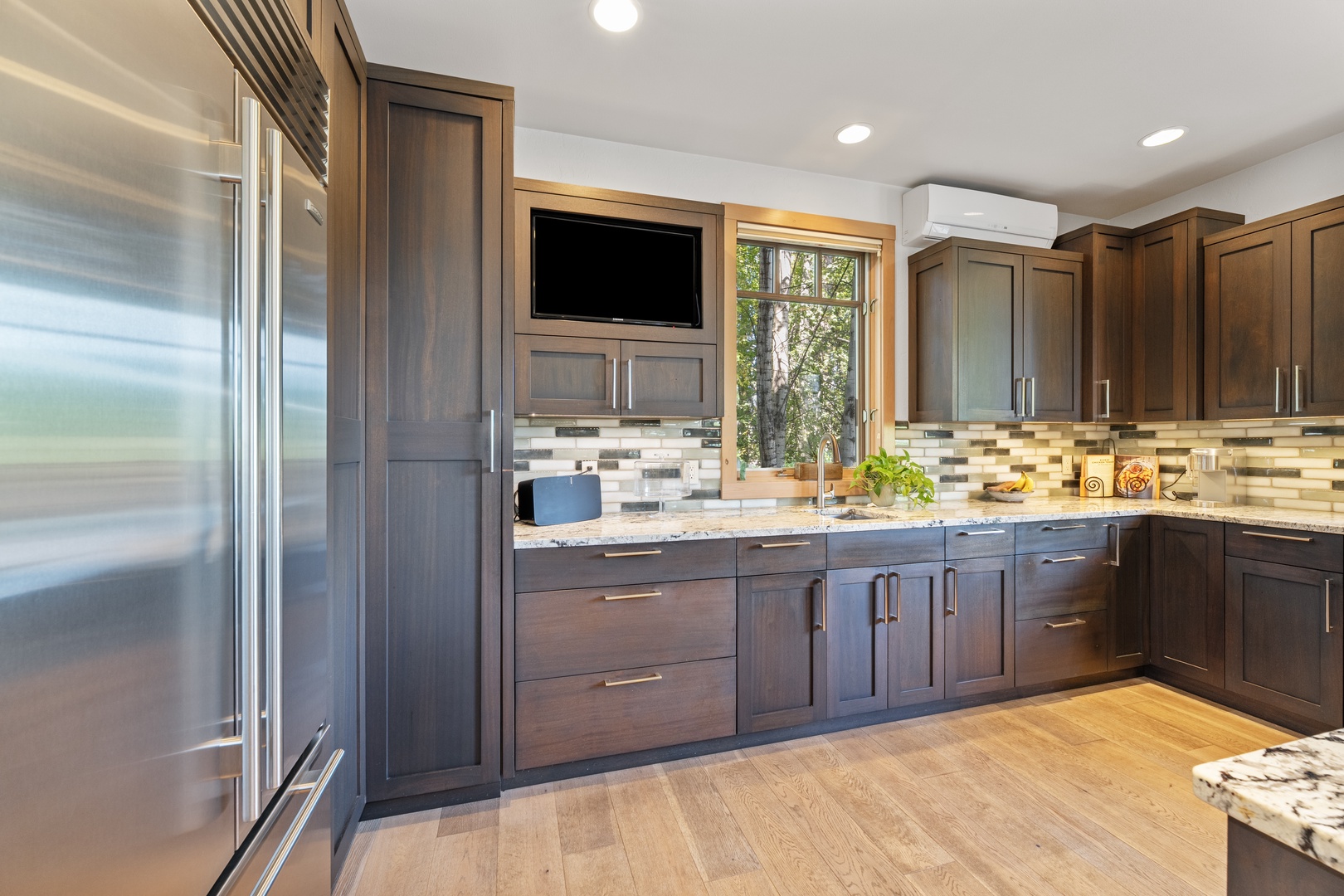 Your gourmet kitchen awaits with rich wood cabinetry, granite countertops, stainless appliances, and modern conveniences. Natural light spills in through the window, illuminating your elegant cooking space.