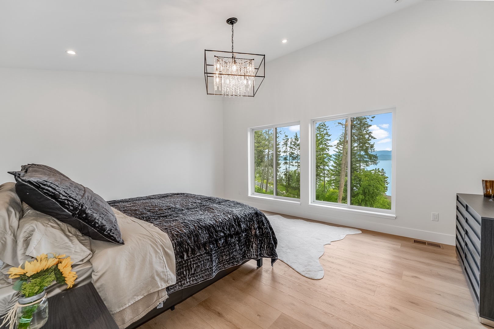 Wake up to stunning lake and forest views through floor-to-ceiling windows. Your peaceful retreat features bright white walls, elegant lighting, and warm wood floors that invite you to relax and recharge.