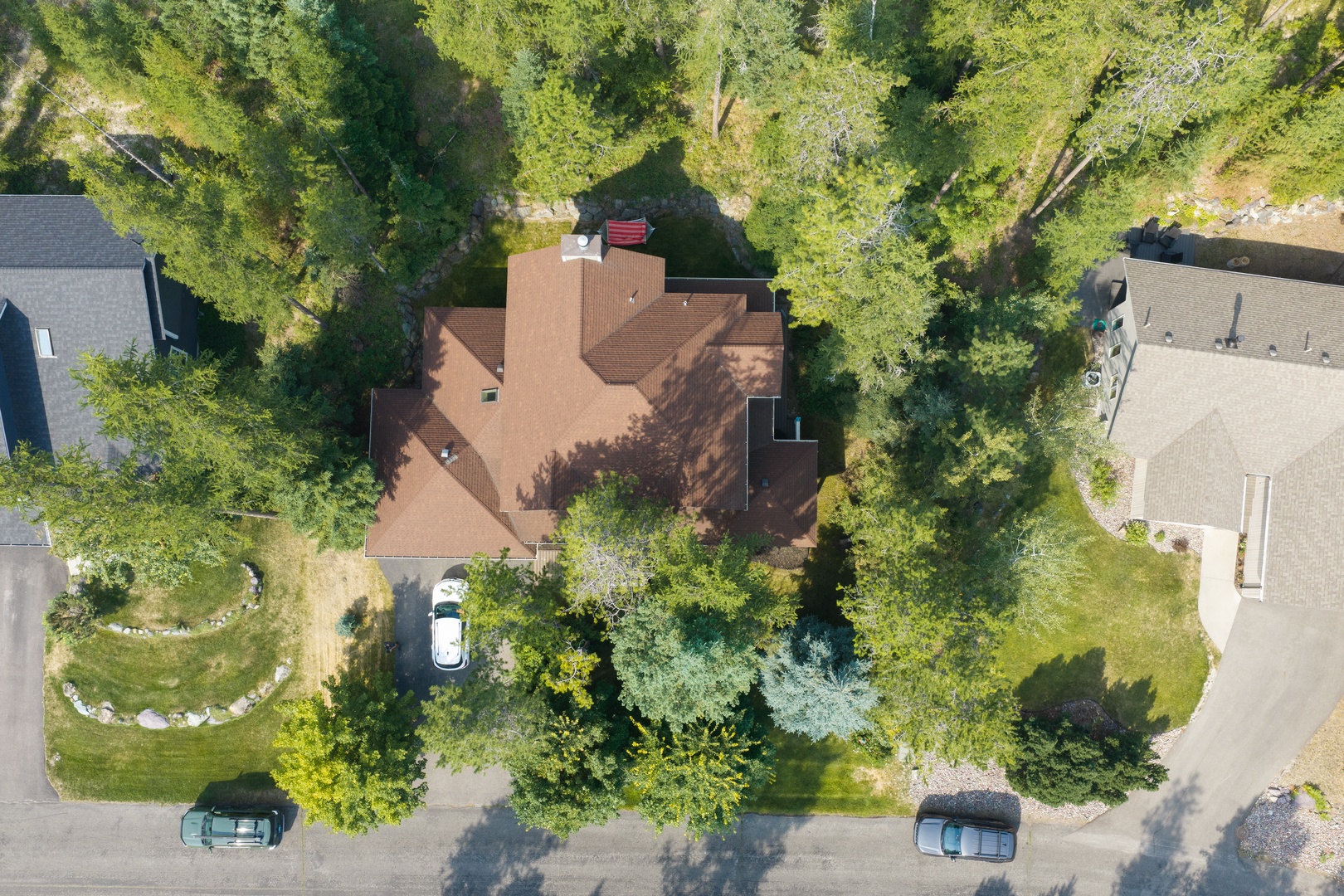 Aerial view of the property nestled in a serene, tree-lined neighborhood with ample parking and lush green surroundings.