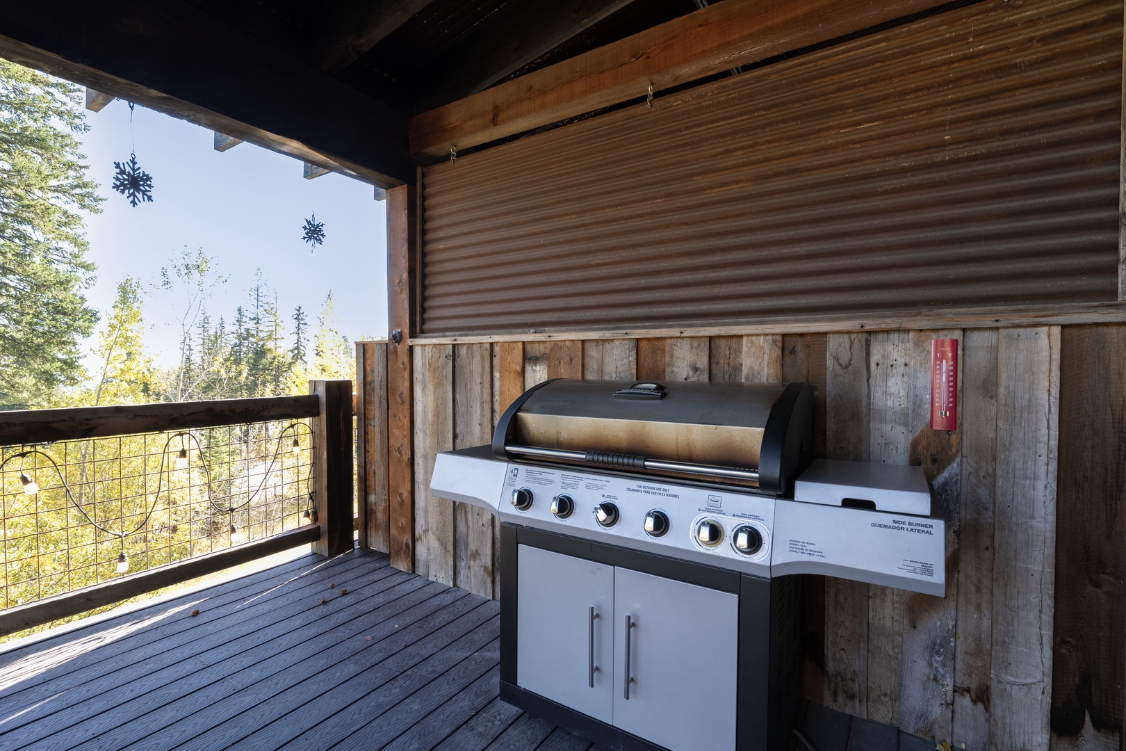 Your covered balcony overlooks forested hillsides, complete with a full-sized grill ready for outdoor cooking. Natural wood tones and open views create a relaxed mountain retreat feel.