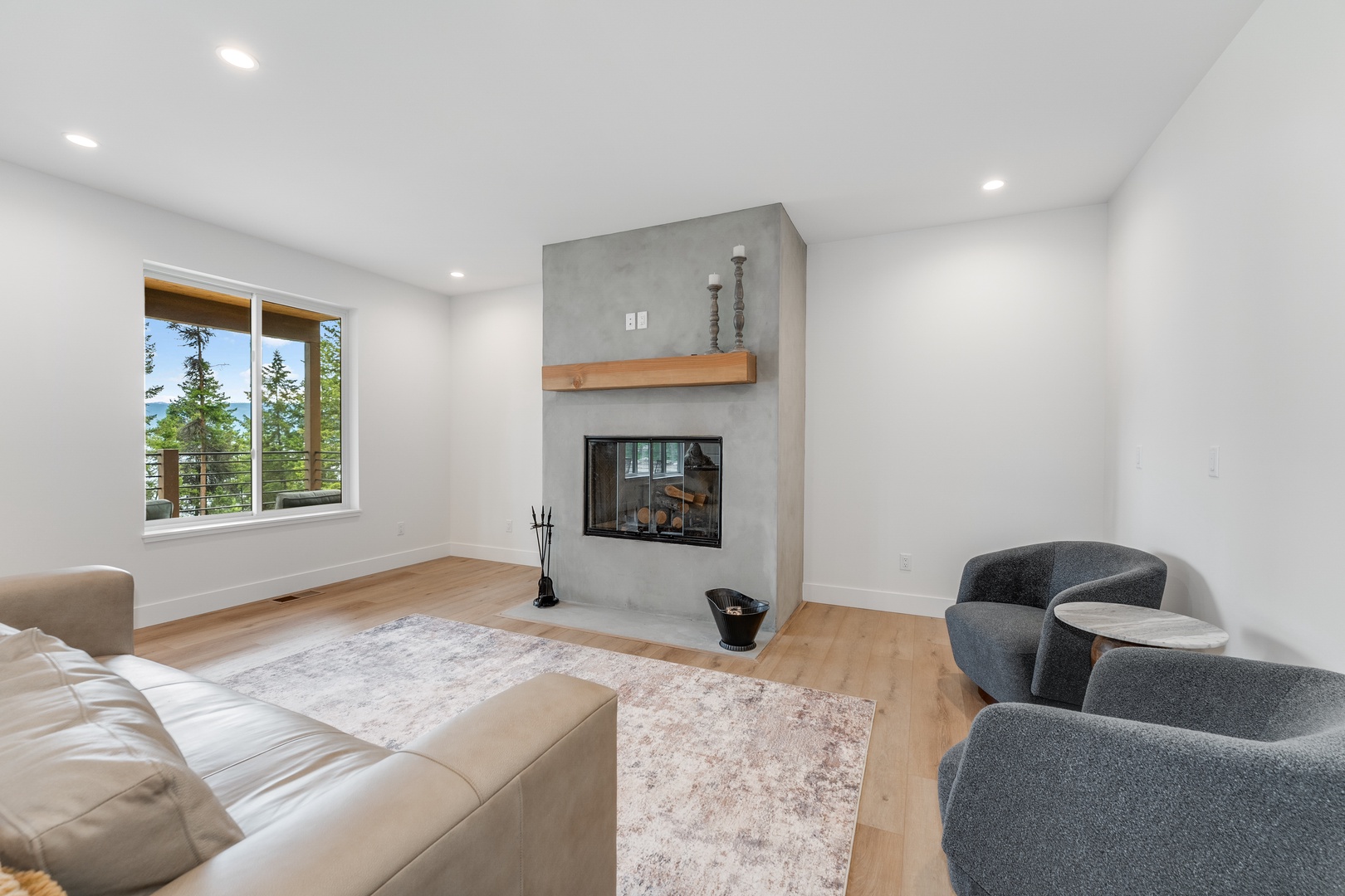 Curl up by the fireplace in this bright, modern living space with mountain views through large windows and warm wood floors underfoot.