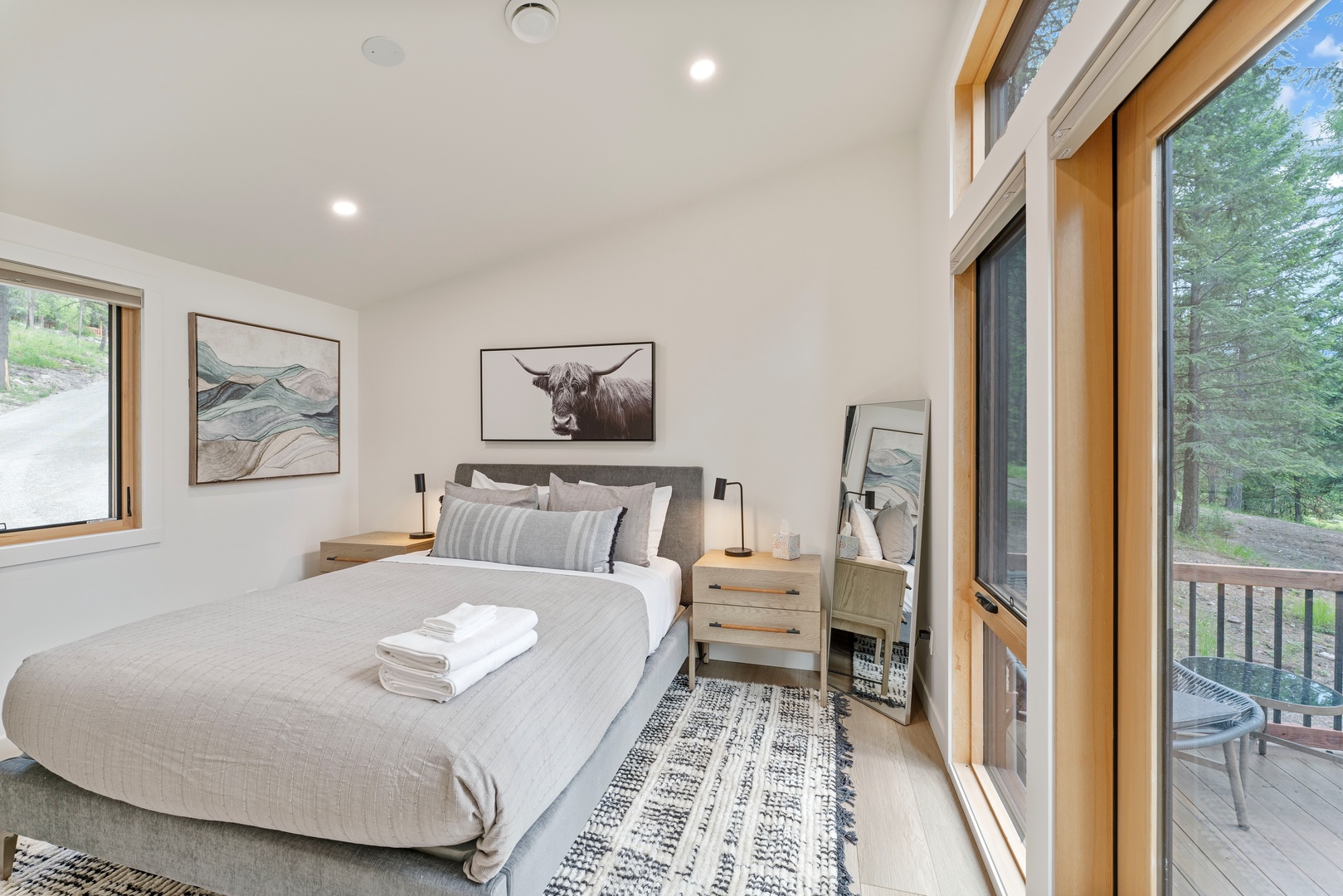Sink into this serene bedroom where natural light streams through floor-to-ceiling windows, and your private balcony beckons for morning coffee with forest views.