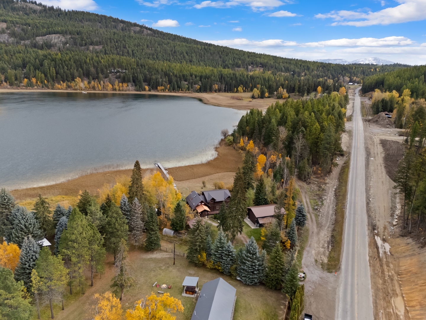 Stunning aerial view showcases the property's lakefront location surrounded by vibrant autumn forests and peaceful mountain scenery.