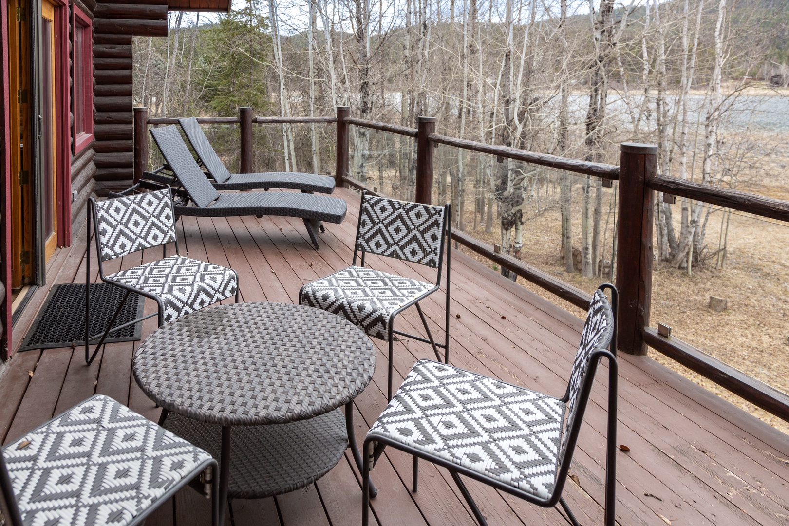 Unwind on your private deck with cozy seating overlooking serene lake views through bare winter trees.
