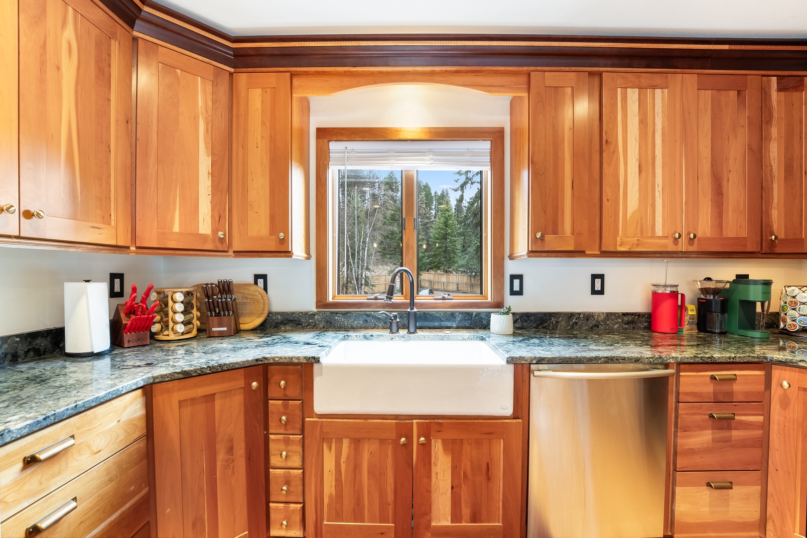 Cook your favorite meals in this spacious kitchen with granite counters, farmhouse sink, and forest views through the window.