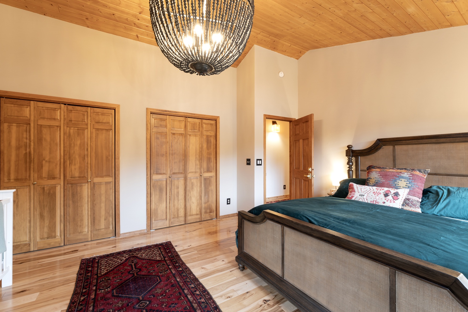 Unwind in your spacious master suite where warm wood accents meet plush bedding under a stunning chandelier.
