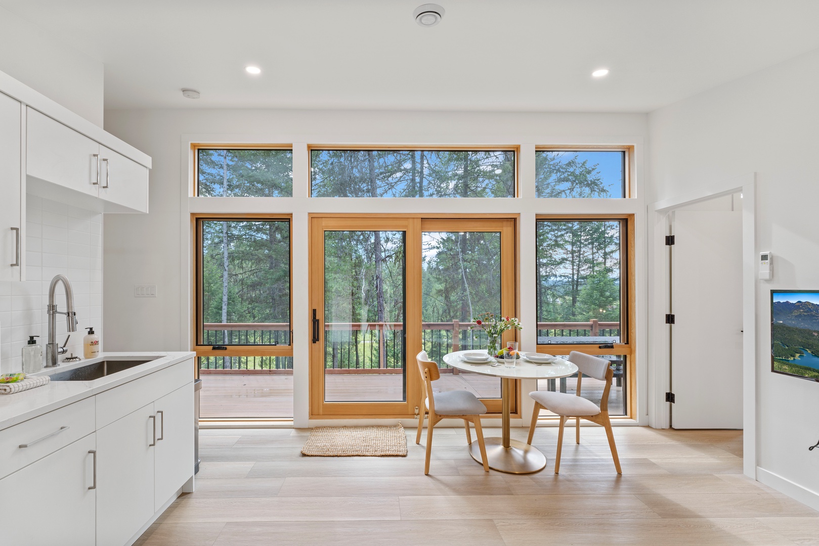 Your bright kitchen opens to a private deck where morning coffee feels magical with forest views stretching endlessly beyond.