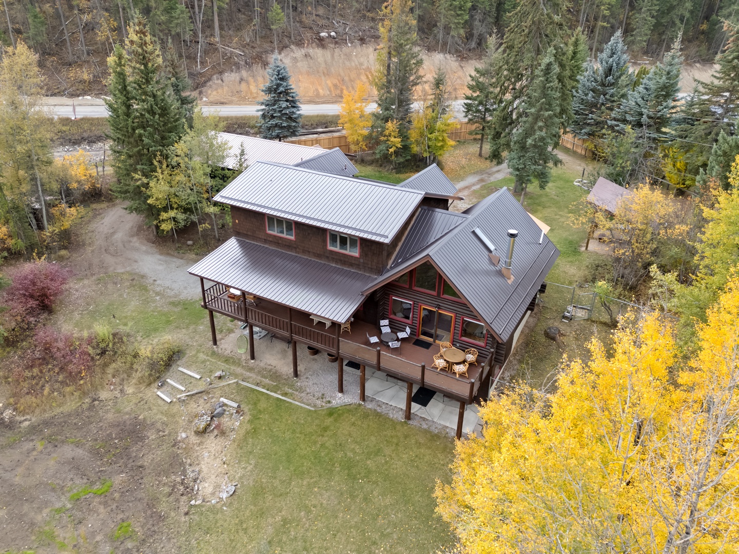 Beautiful mountain cabin surrounded by vibrant autumn foliage and towering evergreens in a peaceful forest setting.
