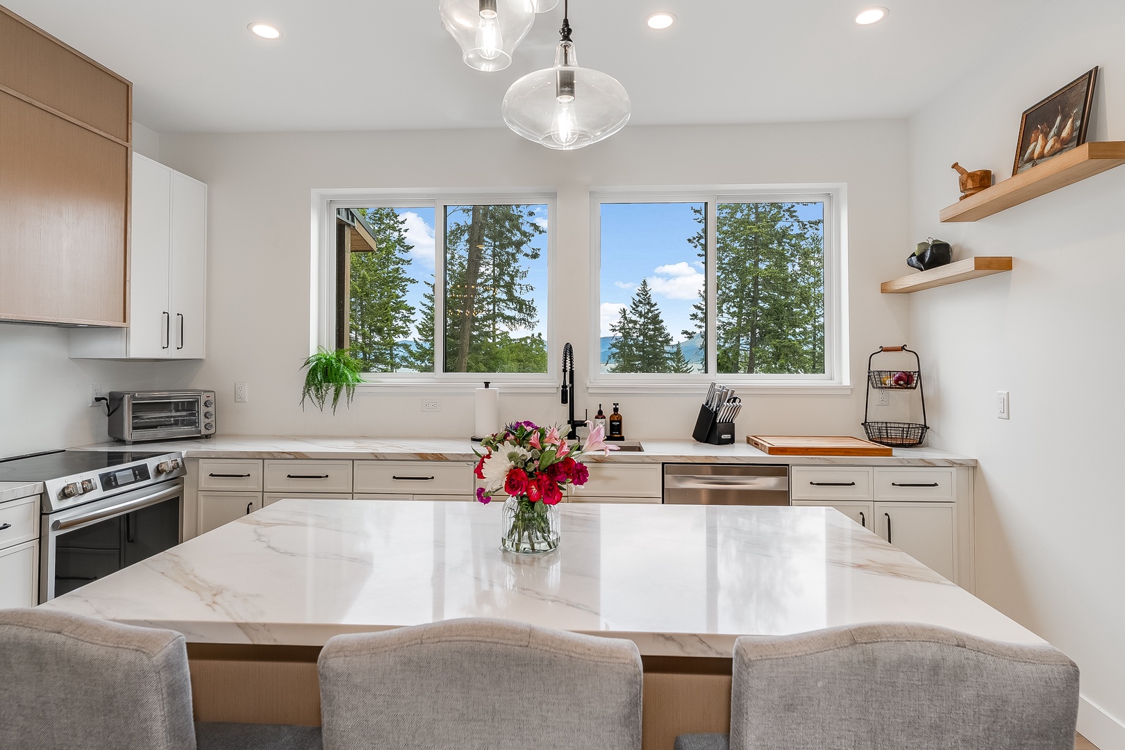 Gather around this sleek kitchen island where meals become memories. Bright windows frame forest and water views, while modern appliances make cooking feel effortless and enjoyable.