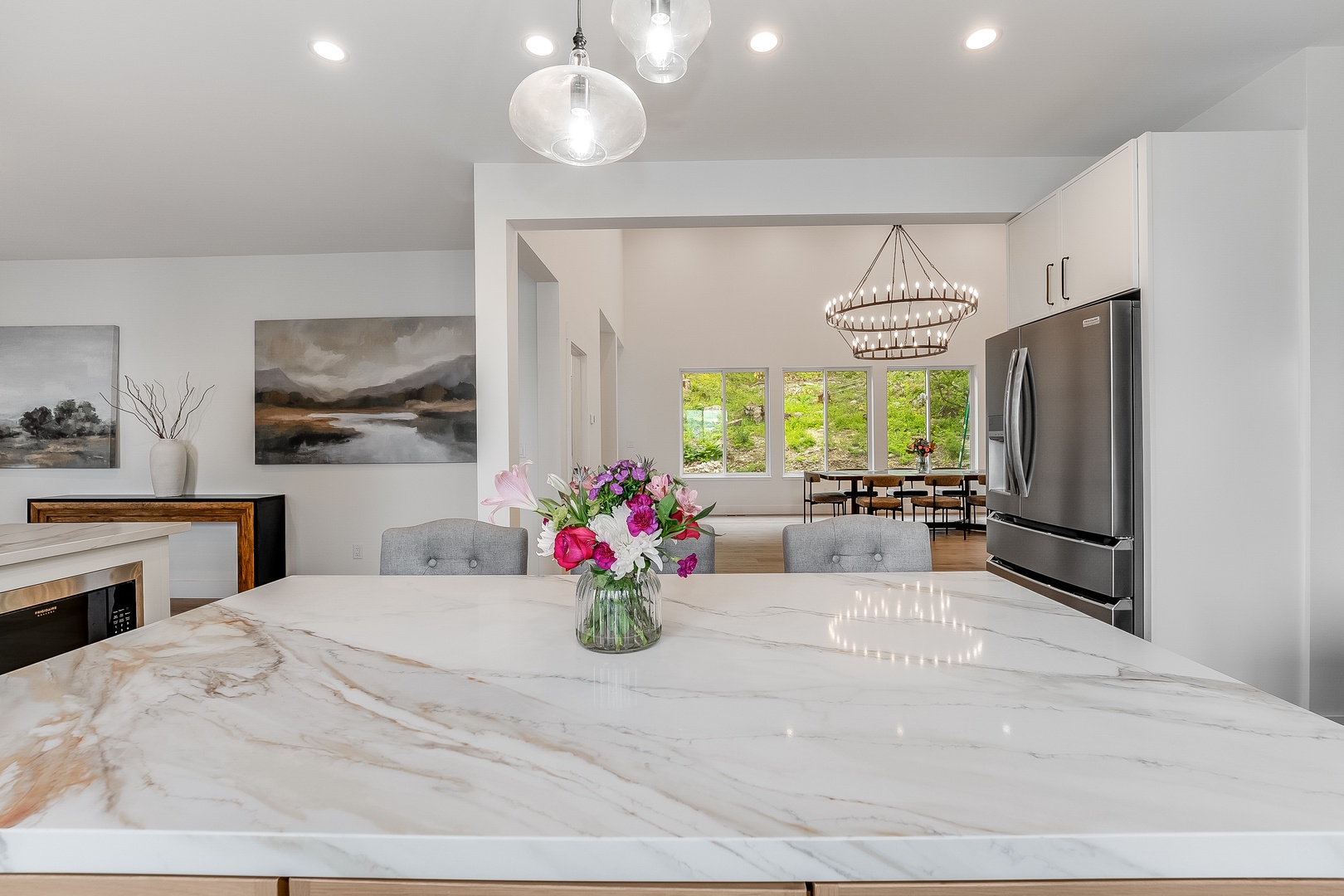 Modern elegance meets comfort in this bright, open-concept kitchen and dining space. Sleek marble countertops, statement lighting, and fresh florals create the perfect backdrop for your culinary adventures and morning coffee.