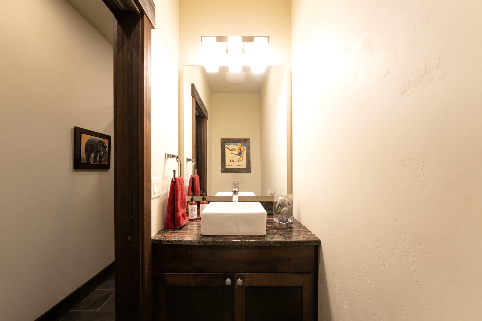 Freshen up in your stylish powder room featuring a modern vessel sink and warm lighting that creates an inviting glow.