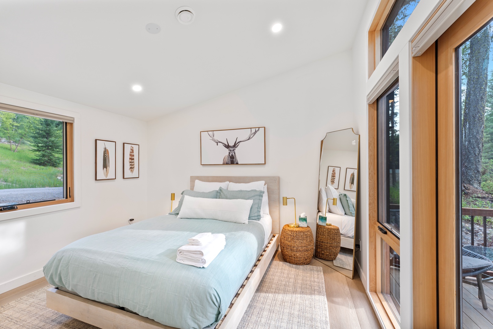 Wake up in your serene retreat with forest views through panoramic windows, plush linens, and peaceful nature artwork creating your perfect escape.