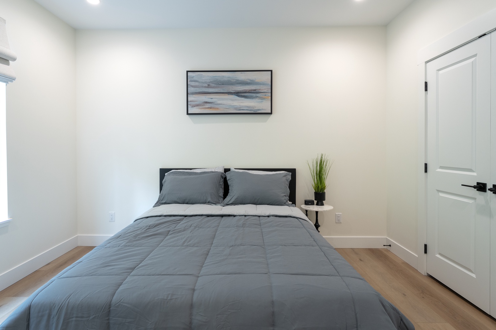 Settle into your serene bedroom retreat with a plush bed and coastal artwork overhead. Light-filled and uncluttered, this space invites deep rest and peaceful mornings.