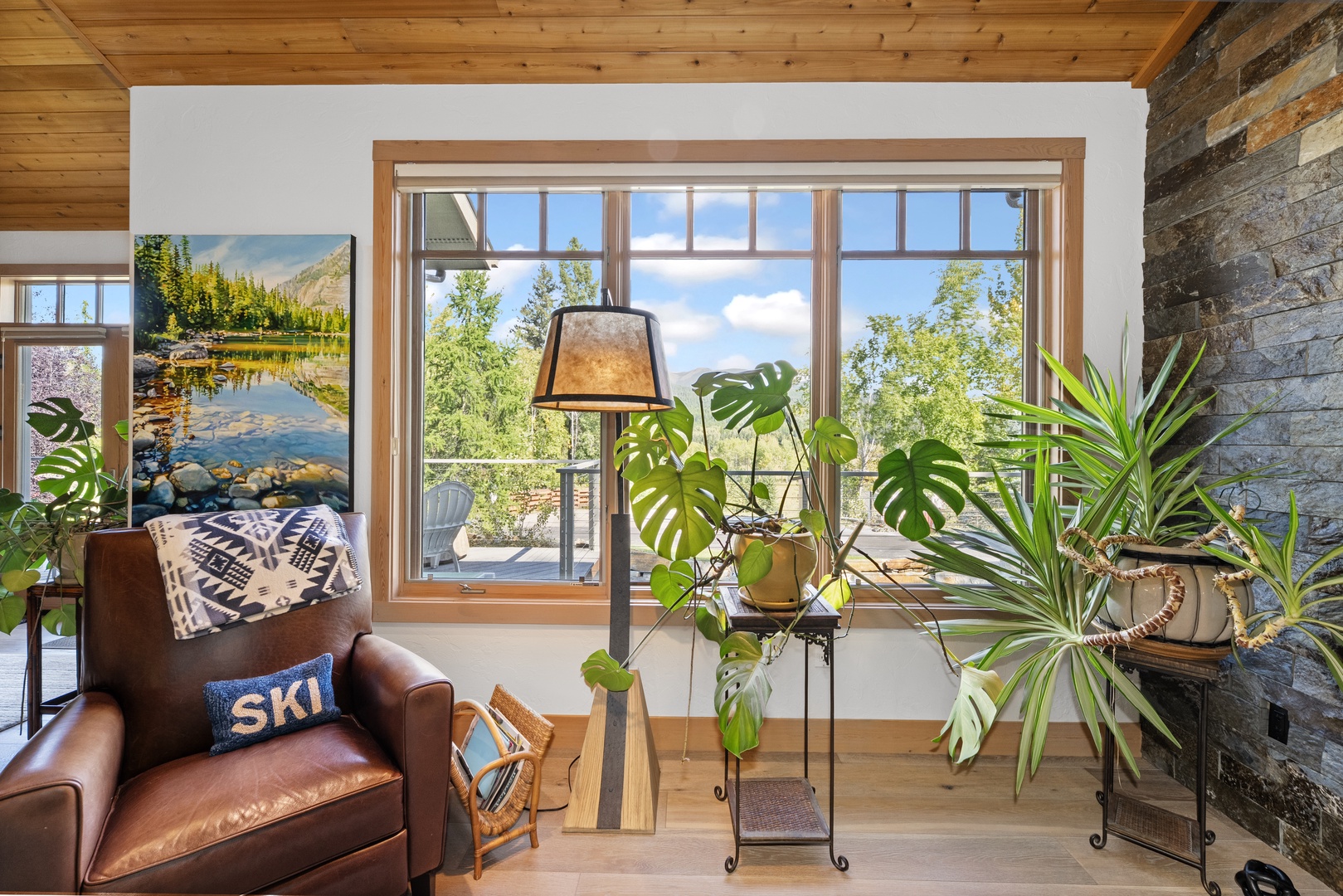 Curl up in this cozy corner with your favorite book, surrounded by lush greenery and framed by sweeping views of leafy treetops through the large picture window.