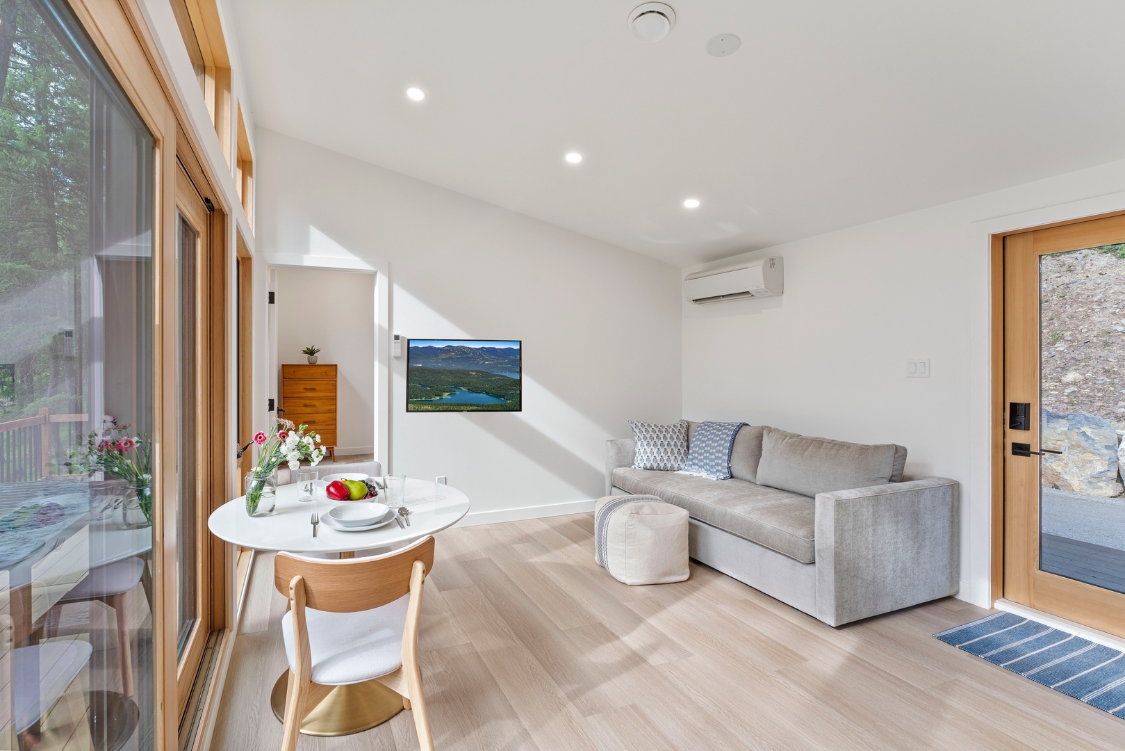 Relax in your bright, modern living space with comfortable seating and dining area, all bathed in natural light from floor-to-ceiling windows.