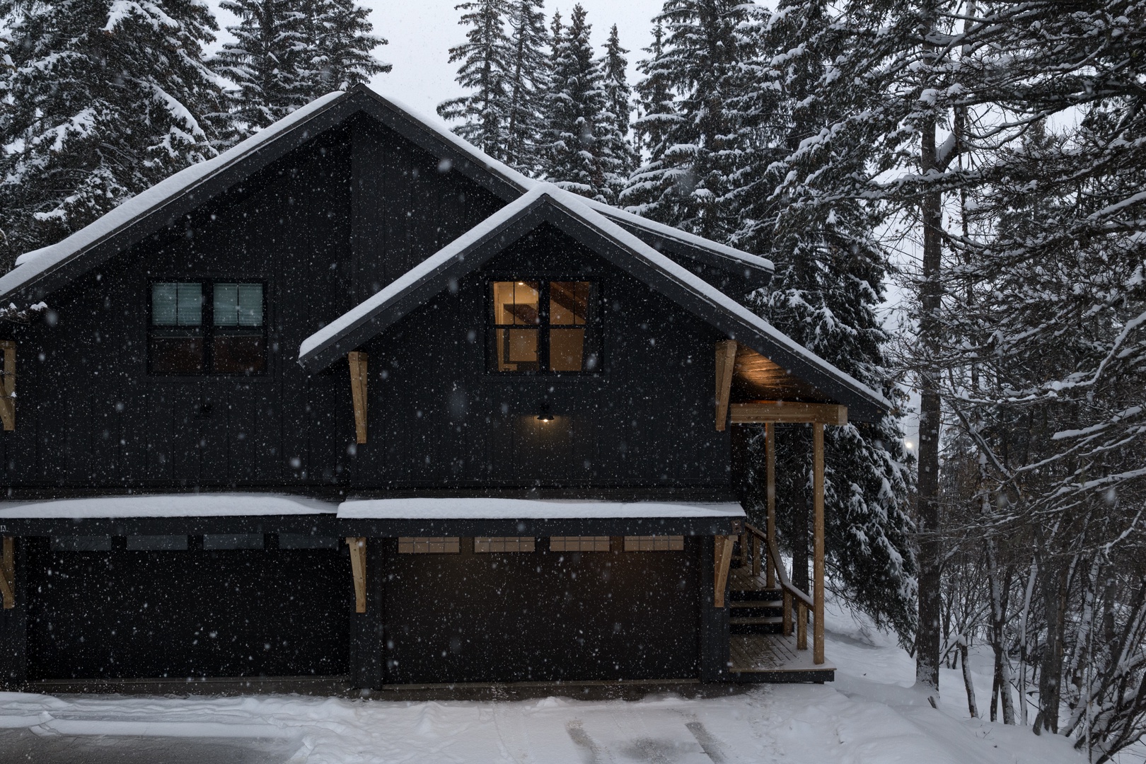 Snow-covered mountain cabin nestled among evergreen trees during a peaceful winter snowfall.