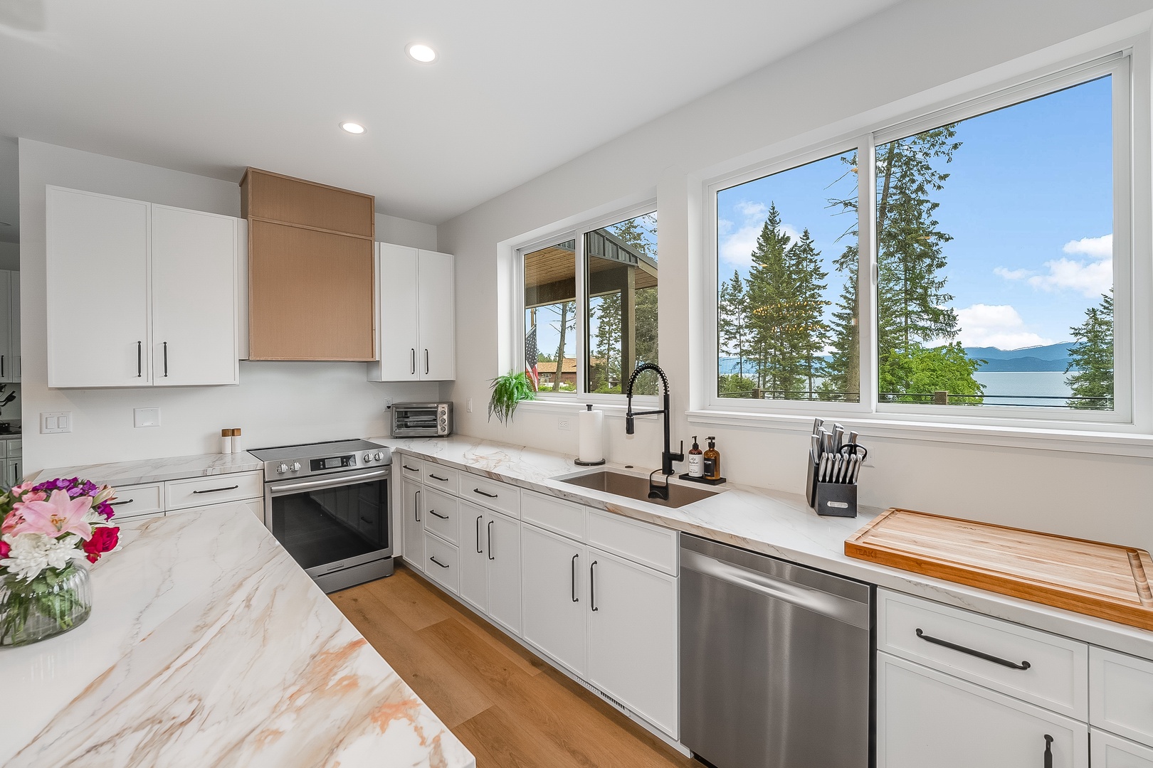 Imagine cooking in this bright, modern kitchen with stunning lake and mountain views right outside your window, blending comfort with natural beauty.