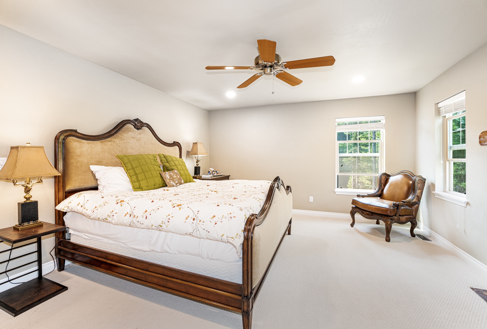 Sink into plush bedding in your sunlit bedroom, where the ceiling fan keeps things comfortable and windows frame peaceful garden views—perfect for your morning coffee and evening relaxation.