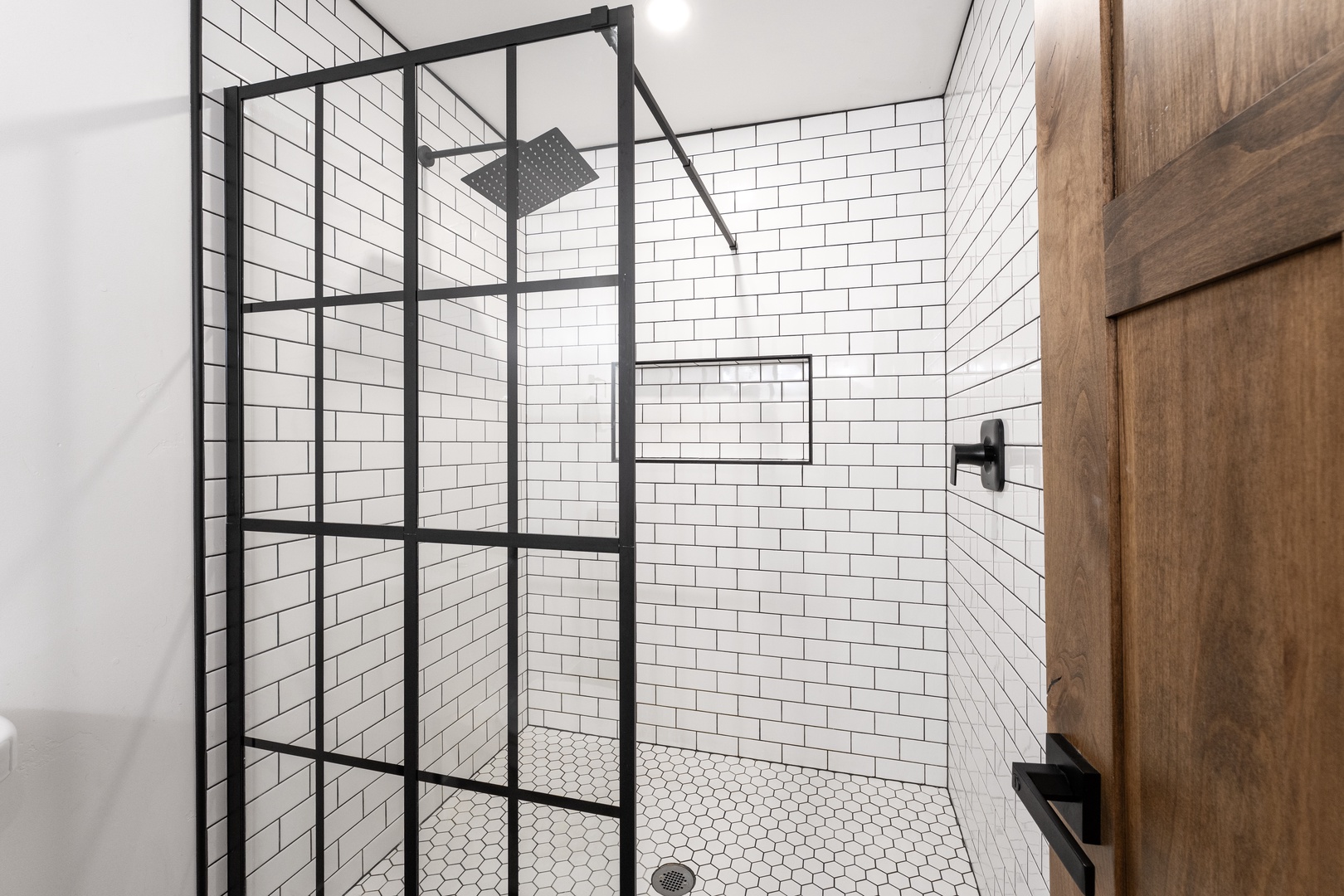 Step into your stylish shower sanctuary with crisp subway tiles and industrial-chic black framing for a refreshing start to each day.