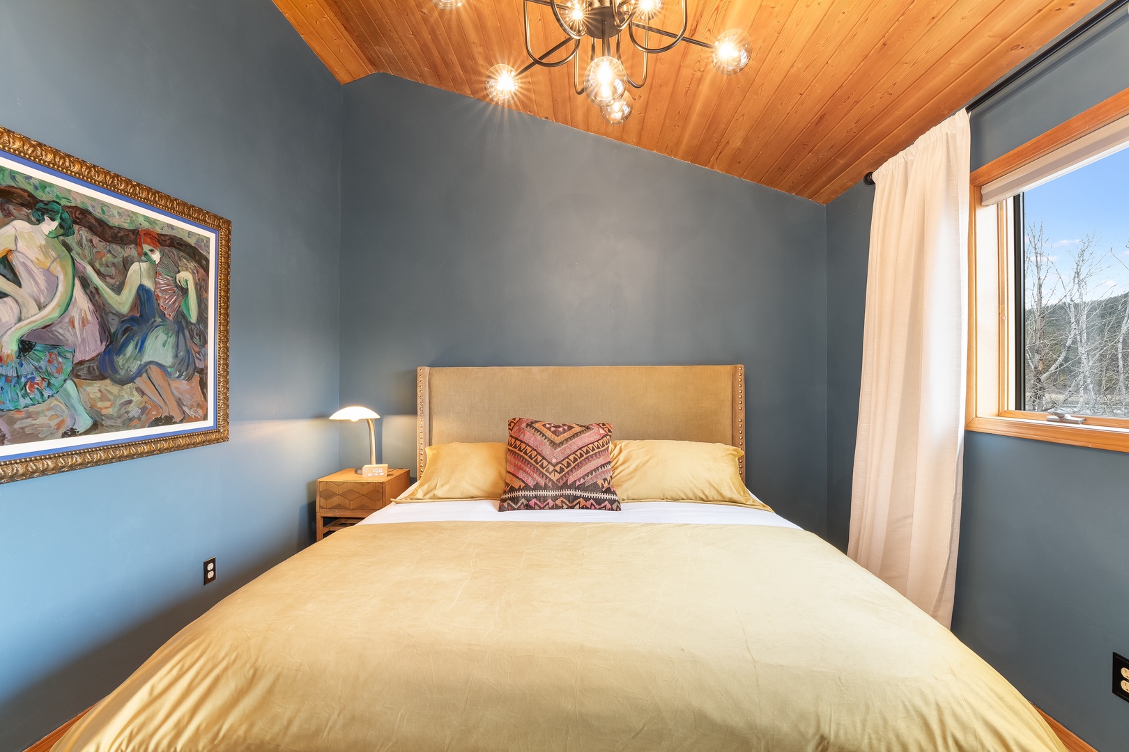 Unwind in your serene bedroom with soft linens, warm wood ceiling, and peaceful mountain views through your window.