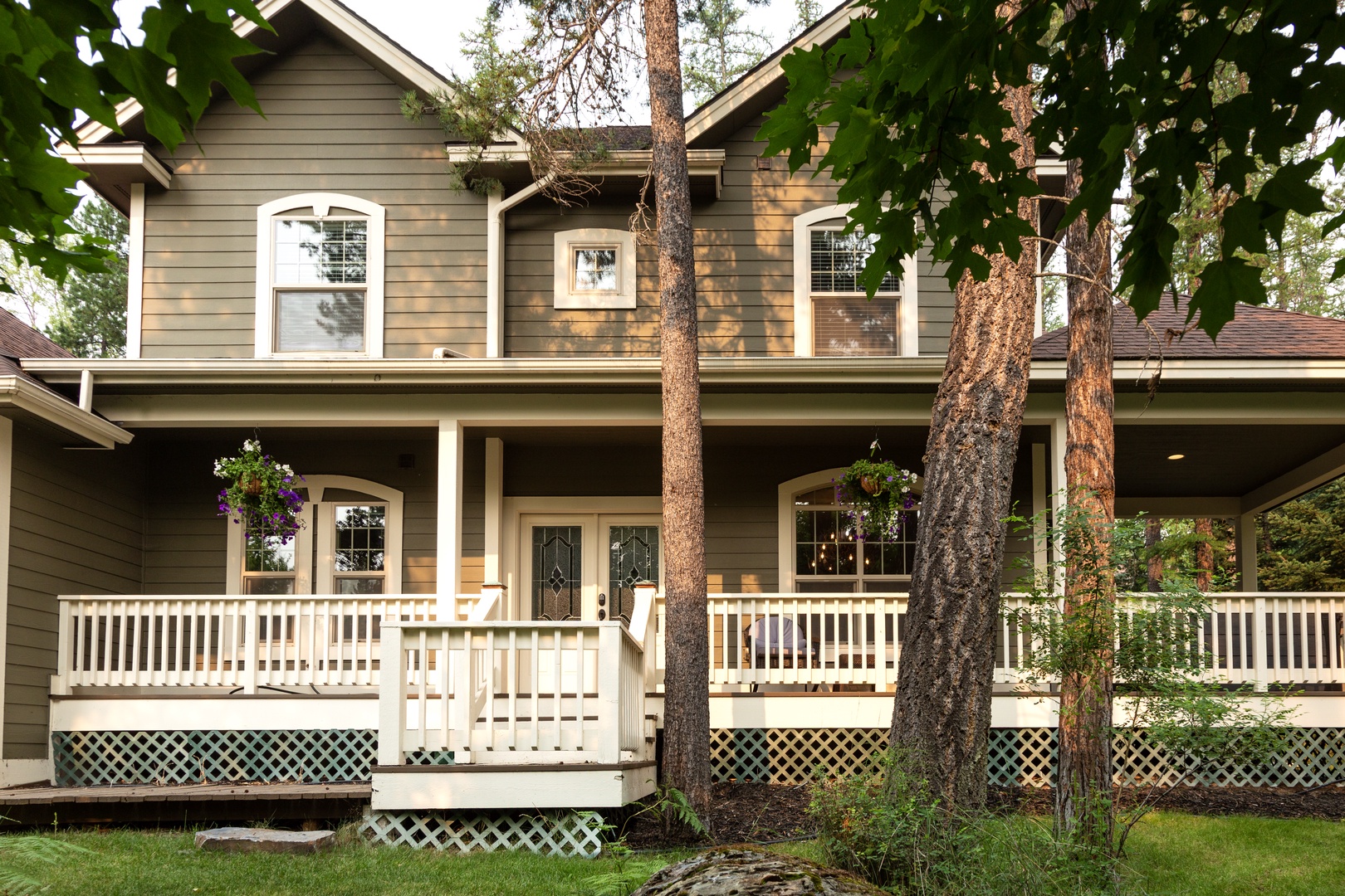 A charming two-story home nestled among towering pines, featuring a welcoming front porch perfect for morning coffee and afternoon relaxation.