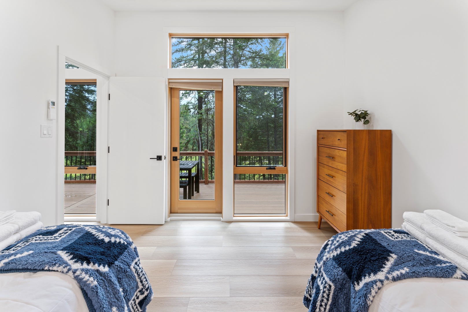 Step onto your private balcony from this bright bedroom and breathe in the fresh forest air through floor-to-ceiling windows.