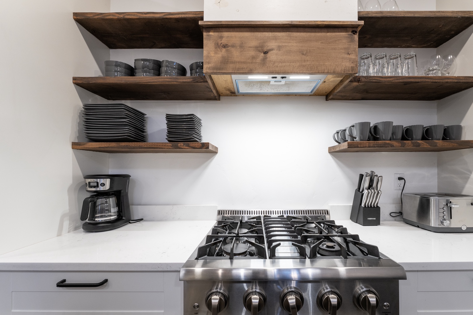 Your fully equipped kitchen awaits with rustic wood shelving, professional gas range, and everything you need to create memorable meals together.