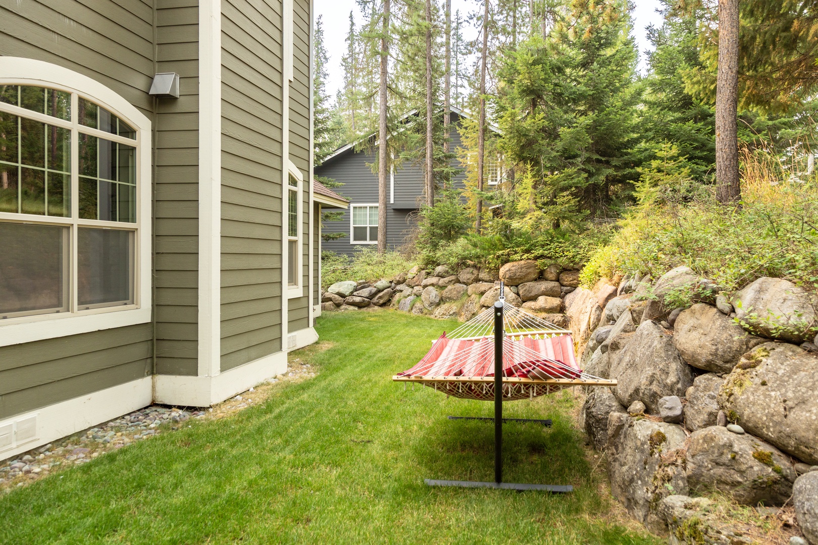 A peaceful hammock awaits in the garden, perfect for afternoon naps or enjoying quiet moments among the trees and natural stone landscaping.