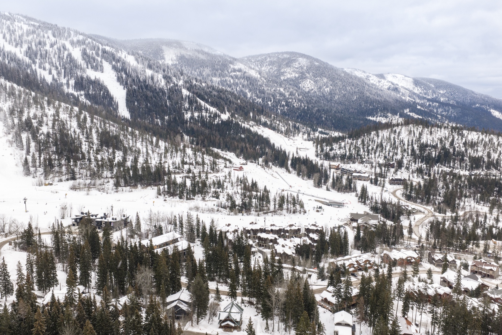 Pristine mountain ski resort nestled in snow-covered peaks and evergreen forests during winter season.