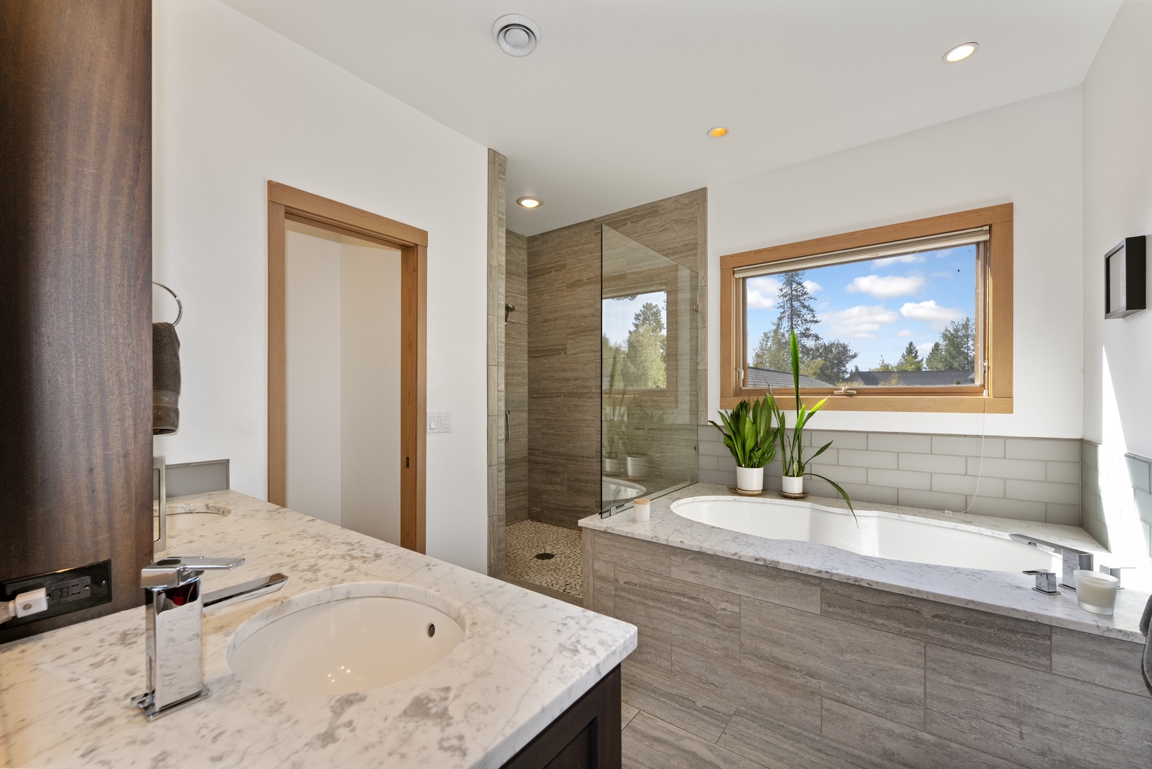 Unwind in your private spa-like bathroom with a soaking tub framed by natural light and a spacious walk-in shower—your perfect retreat after a day of adventure.