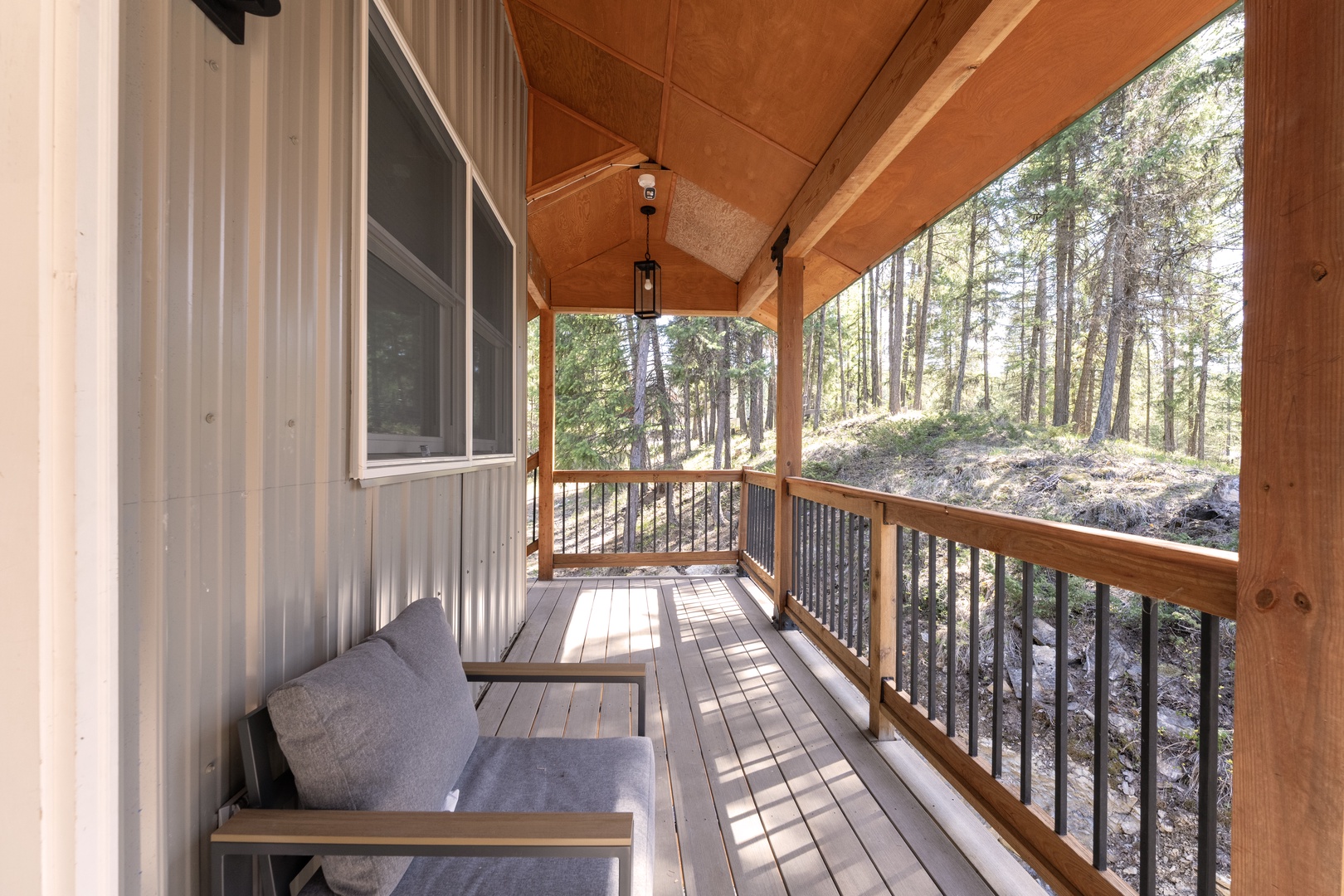 Relax on your private covered deck surrounded by tall pines and peaceful forest views, the perfect spot to unwind after a day of adventure.