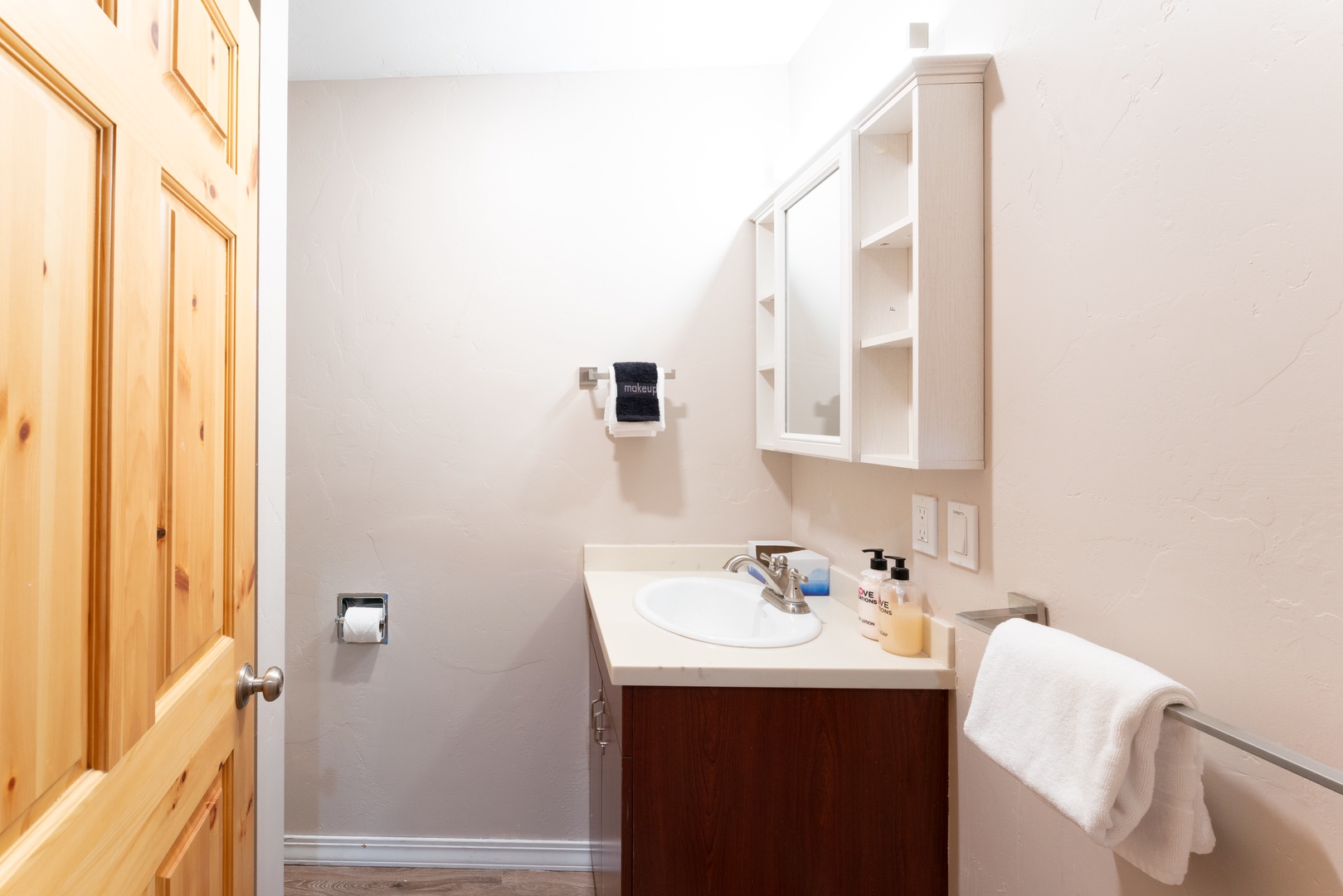 Freshen up in your private bathroom with a clean vanity, storage cabinet, and fluffy towels ready for your stay.