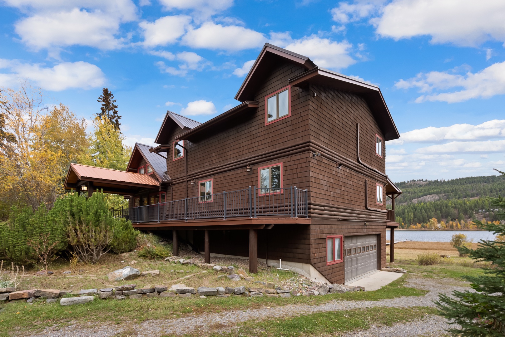 Stunning lakefront mountain retreat featuring natural wood siding and expansive deck overlooking pristine waters and forested hills.