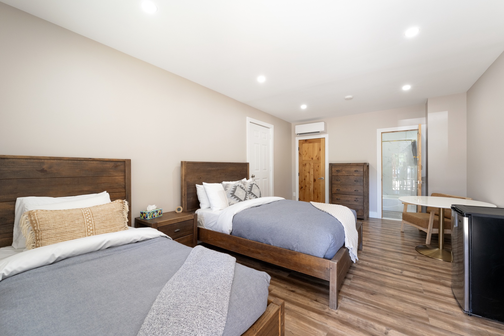 Stretch out in this spacious bedroom with two plush beds, warm wood tones, and modern comfort. Your restful retreat features climate control and ample space to unwind.