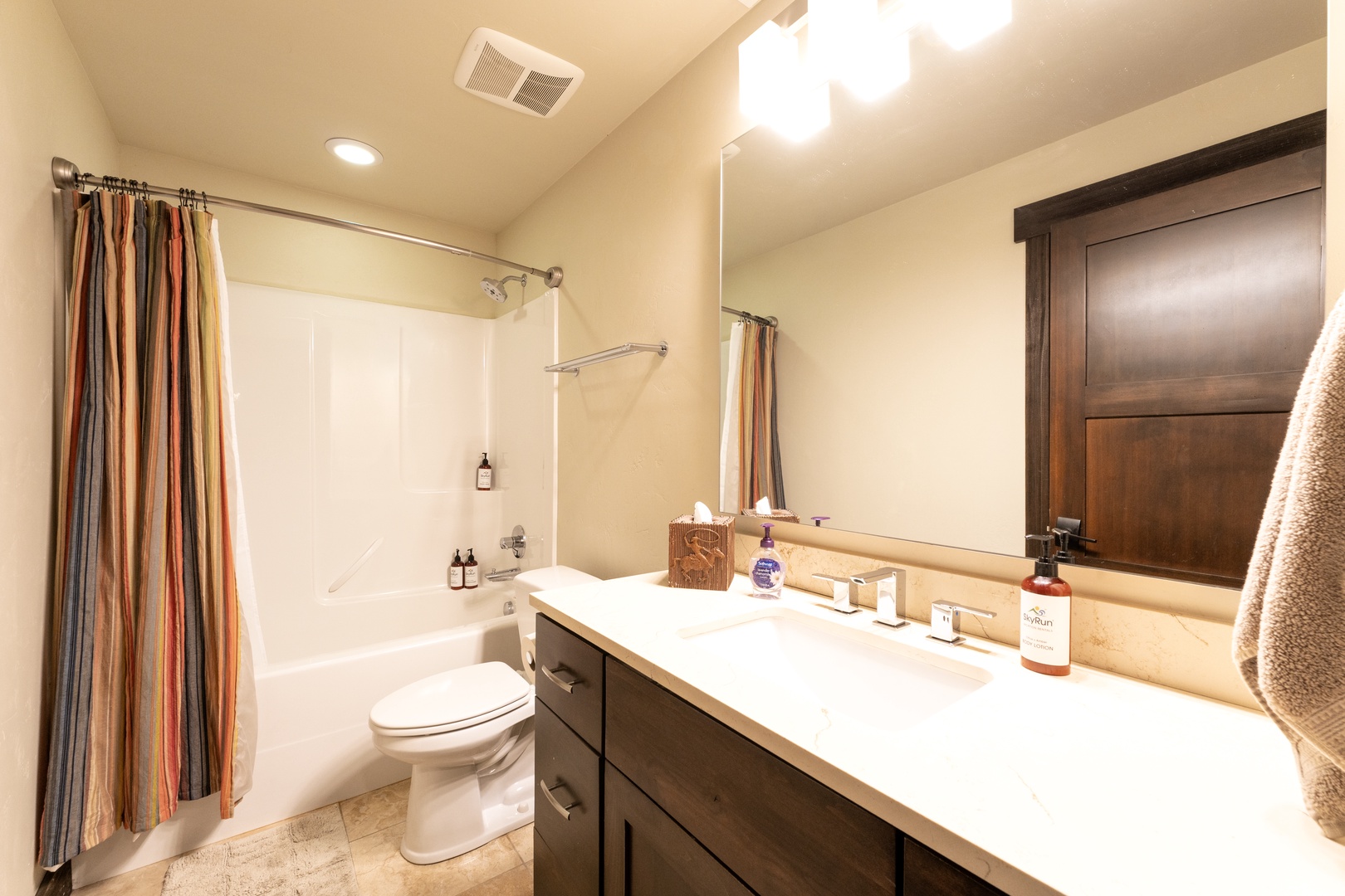 Your private bathroom features a deep soaking tub, crisp white vanity, and warm wood accents that make freshening up feel like a retreat.