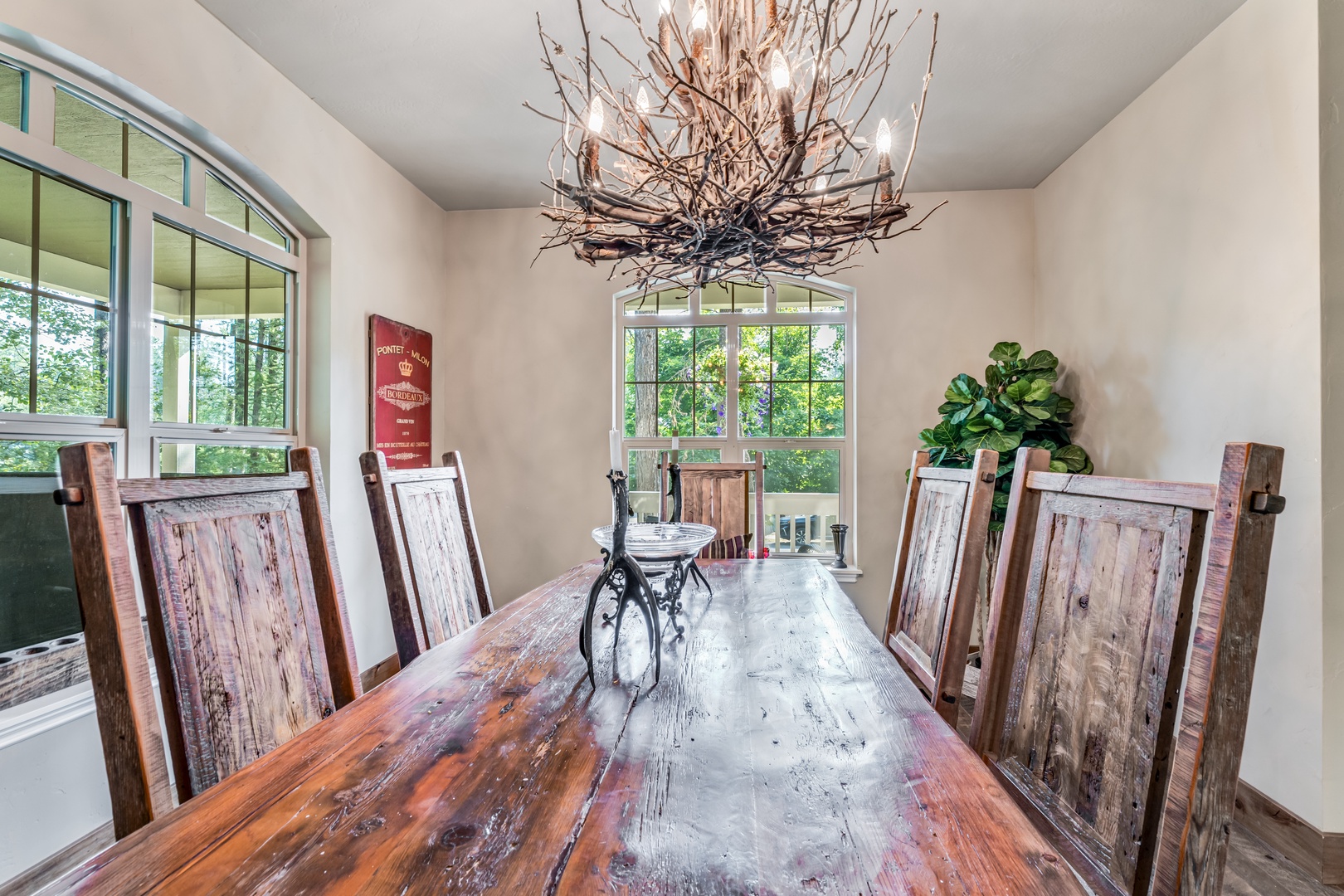 Gather around this handcrafted dining table beneath a stunning rustic chandelier, with views of surrounding trees framing your meals together.